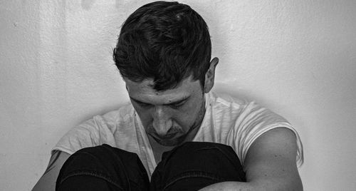 Portrait of man sitting against wall at home