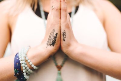 Midsection of woman with tattoo praying