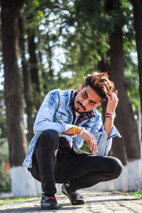 Young man looking away while sitting on tree