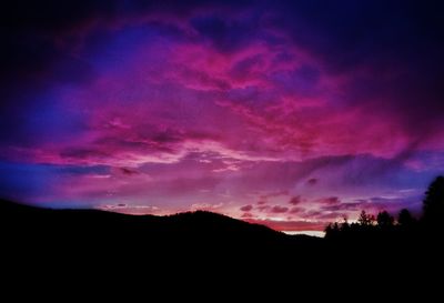 Silhouette landscape against dramatic sky during sunset