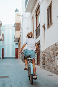 Side view of woman riding bicycle on street in city