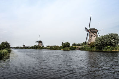 Traditional windmill by lake against sky