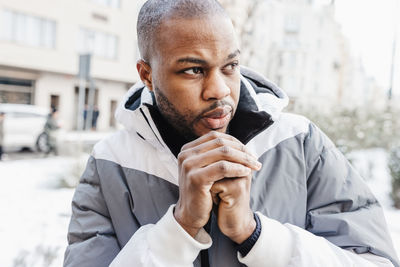 Young african man warming his cold hands with breath in winter