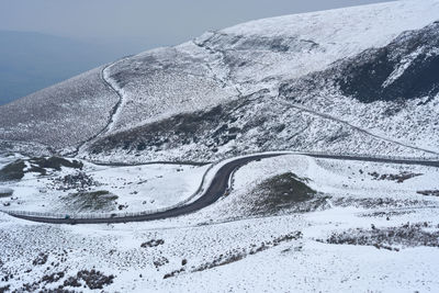 Snow covered road by mountain against sky