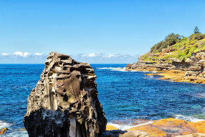 Rock formation on beach against sky