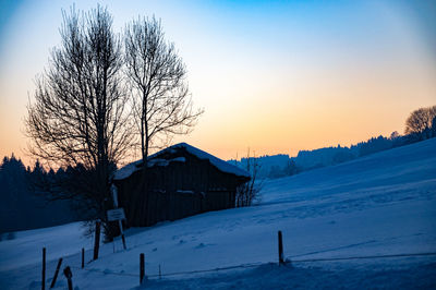 Snow covered landscape against sky during sunset