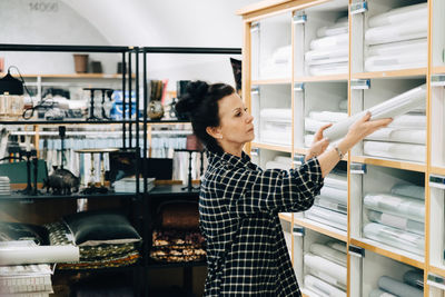 Side view of saleswoman arranging wallpaper in rack