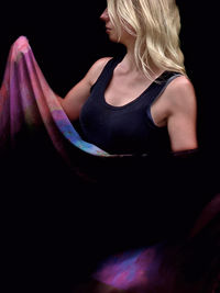 Midsection of young woman against black background