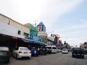 Cars on road by buildings against sky