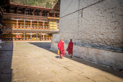 Rear view of men walking in temple against building