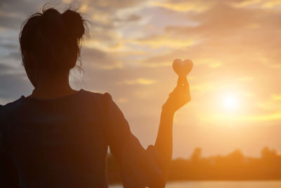 Rear view of silhouette woman standing against sky during sunset