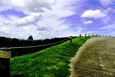 Panoramic shot of road amidst field against sky