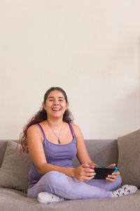 Portrait of young woman sitting on sofa at home