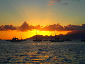 Boats in sea at sunset