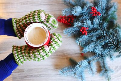 Midsection of woman holding coffee at christmas tree during winter