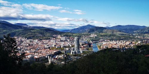 Aerial view of townscape by mountains against sky