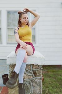 Full length of young woman sitting on retaining wall