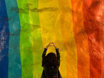 Rear view of man standing against multi colored wall