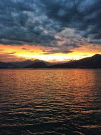 Scenic view of lake against dramatic sky during sunset