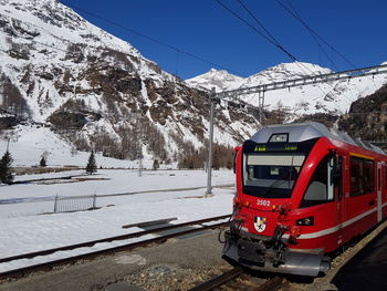 Train on railroad track by snowcapped mountains during winter