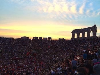 People at historic building in city against sky during sunset