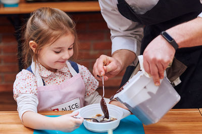 Girl looking at chocolate being poured by man in bowl