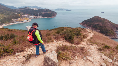 Man standing on mountain by sea