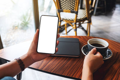 Cropped hands using mobile phone while sitting on table