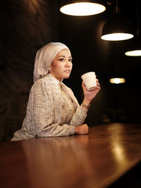 Portrait of young woman sitting on table