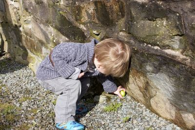 High angle view of boy picking food against rock