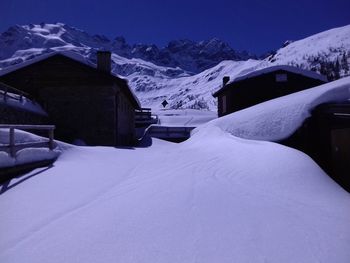 Snow covered houses and mountains against sky