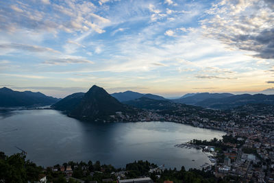 Aerial view of bay and mountain by cityscape against sky during sunset