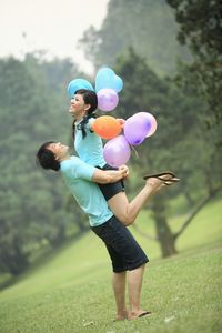 Couple lover with balloons hugging on greenfield 