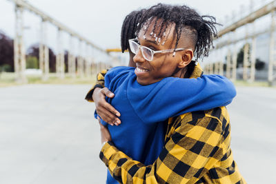 Smiling young man wearing eyeglasses hugging friend