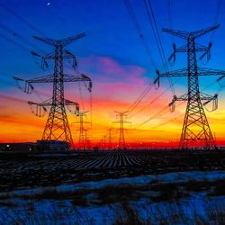 Low angle view of electricity pylon against sky during sunset