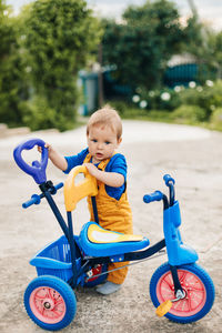 A small boy stands next to a child's tricycle. first bike, new skills
