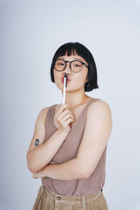 Portrait of young woman holding camera over white background