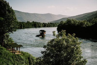 Scenic view of lake by tree mountains against sky