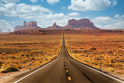 Road leading towards mountains against sky