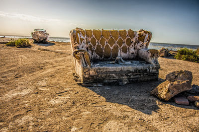 Abandoned couch at beach against clear sky