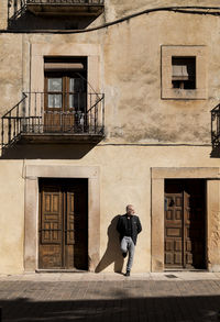 Man in black suit standing against old building