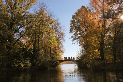 Arch bridge over river against sky during autumn