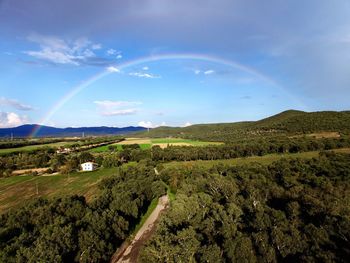 Scenic view of rainbow over green landscape against sky