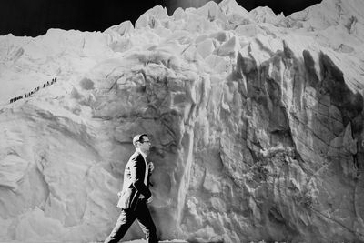 Full length of woman standing on snow covered rock