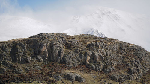 Rock formations on snowcapped mountain against sky