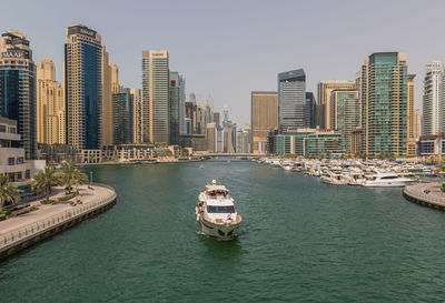 Boats in sea by buildings against sky in city