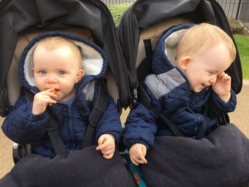 Cute baby boys sitting in baby carriages