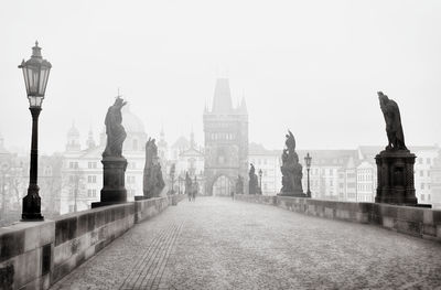 Statues on a stone bridge against sky