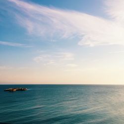 Boats in calm sea against cloudy sky