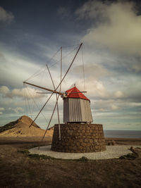 Traditional windmill on beach against sky